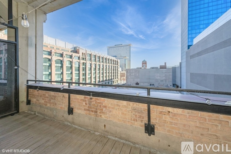 A balcony with a brick wall and a wooden floor overlooks a cityscape.