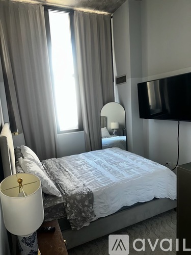 A bedroom with a bed, a lamp, and a television.