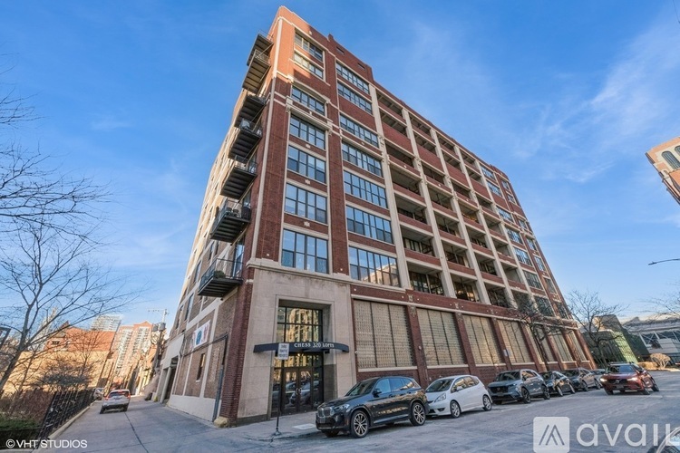 A tall red brick building with a parking lot in front.