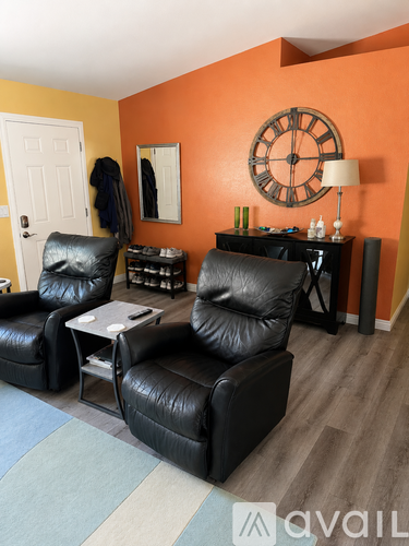 A living room with two black leather chairs and a wooden table.