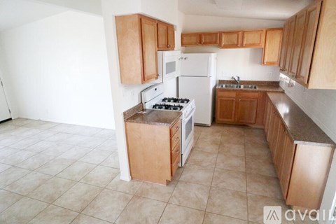 A kitchen with a white refrigerator, a white stove, and wooden cabinets.