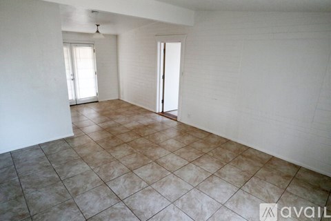 A room with tiled flooring and two open doors.