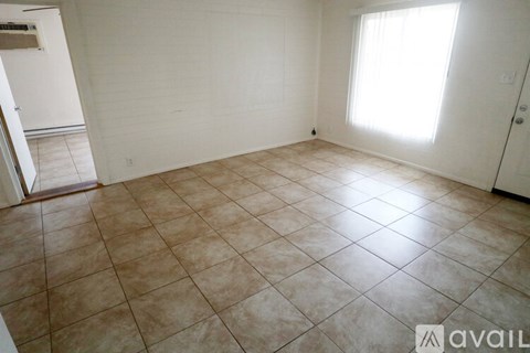 A room with tiled flooring and a window letting in sunlight.