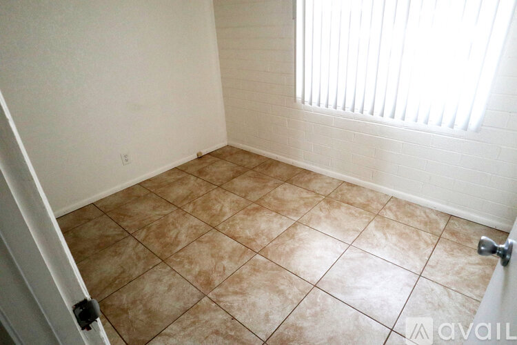 A room with tiled flooring and a window with blinds.