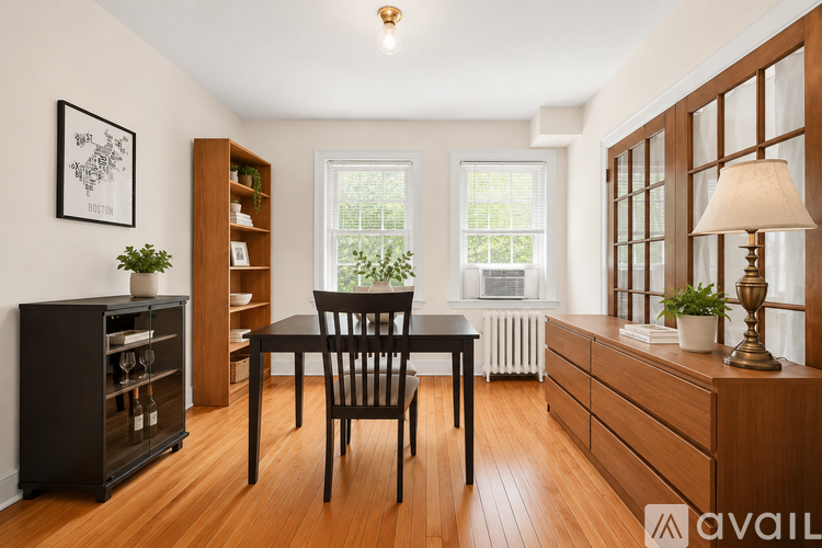 A well-lit room with a dining table and chairs, a bookshelf, and a cabinet with a plant on top.
