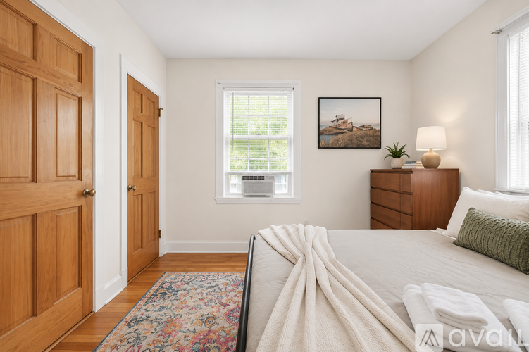 A bedroom with a bed, dresser, and a window with a view of a tree.