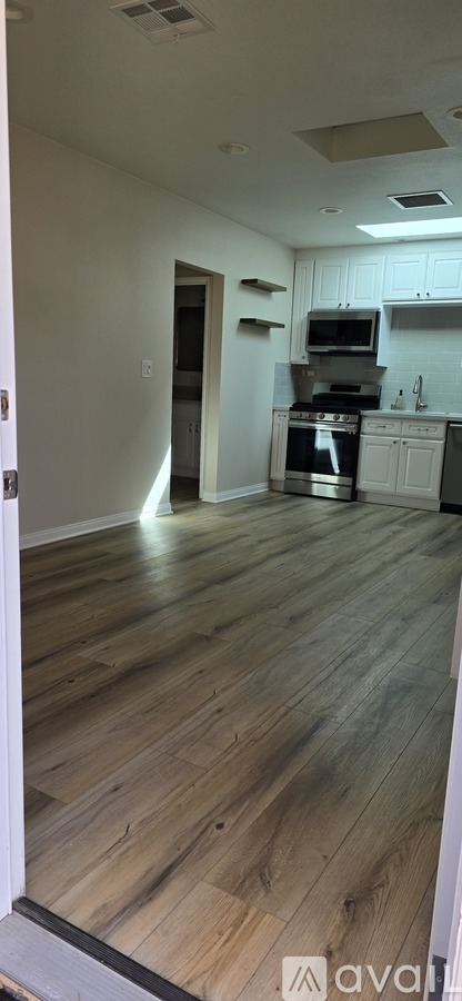A kitchen with white cabinets and a stainless steel refrigerator.