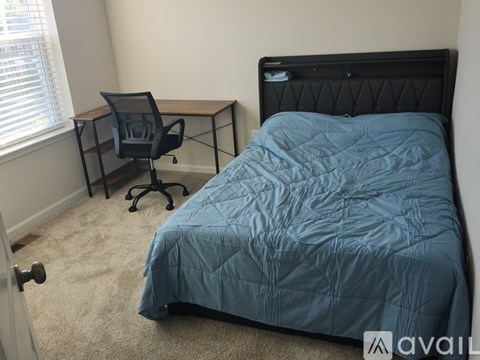 A bedroom with a bed, desk, and chair.