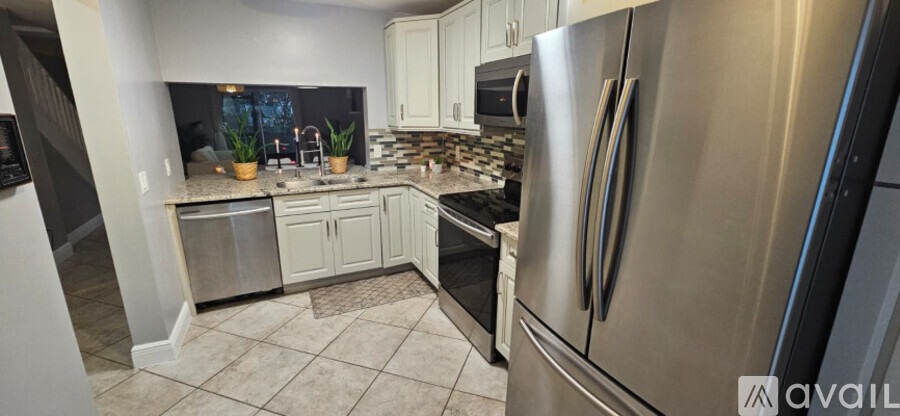 A kitchen with a stainless steel refrigerator and white cabinets.