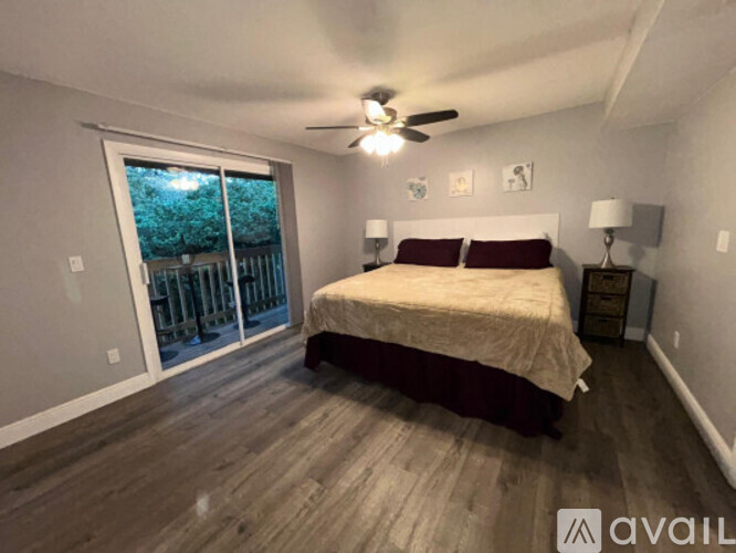 A bedroom with a bed, a ceiling fan, and a sliding glass door.