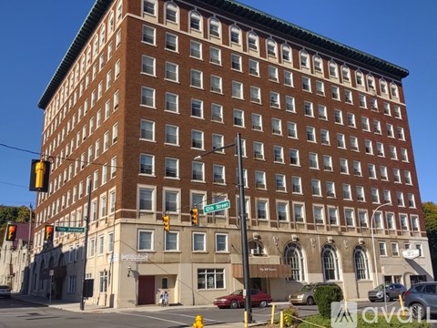 A large brown building with many windows is situated on a street corner.