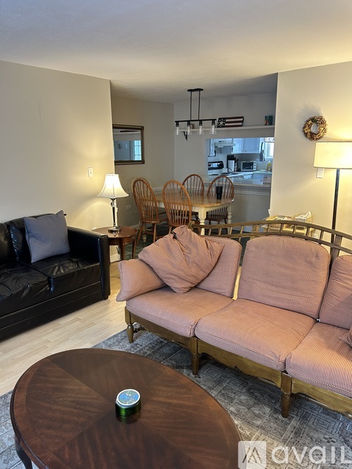A living room with a black couch, a wooden coffee table, and a pink sofa.