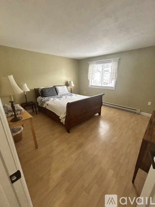 A bedroom with a bed, two lamps, and a window.