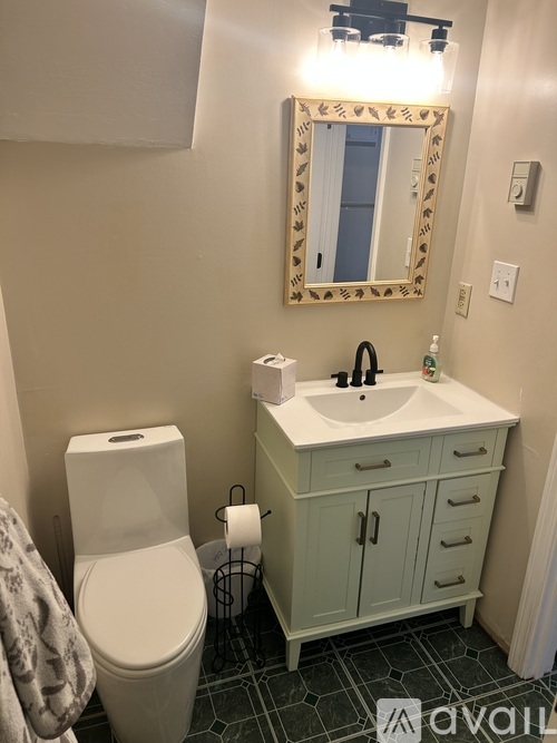 A bathroom with a toilet, sink, and mirror.