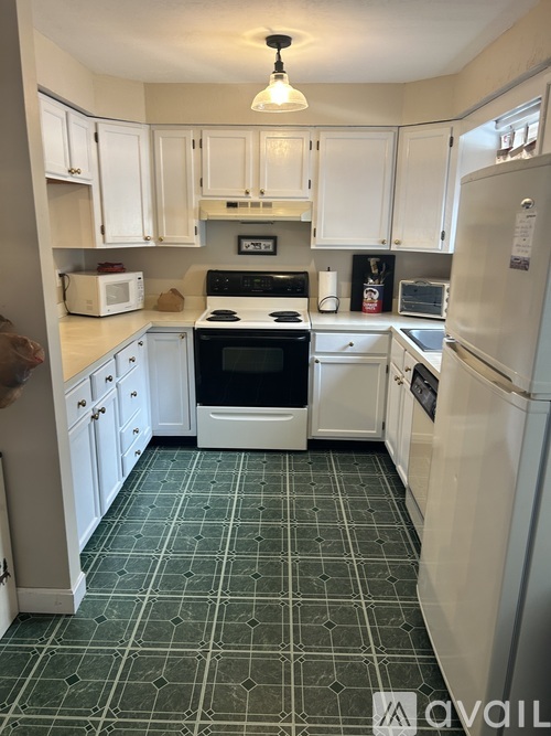 A kitchen with white cabinets and green floor tiles.