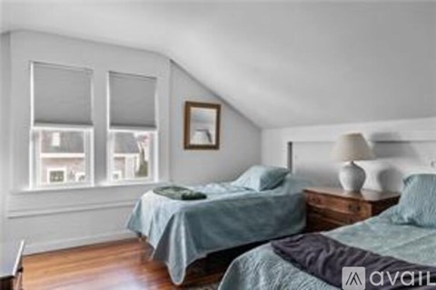 A bedroom with two beds and a window with blinds.
