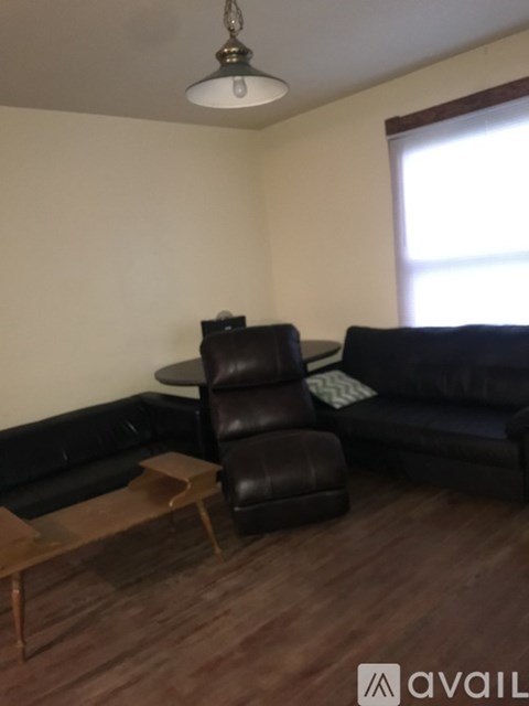 A living room with a black leather couch and a wooden coffee table.