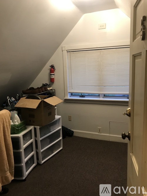 A room with a box on a shelf and a fire extinguisher on the wall.