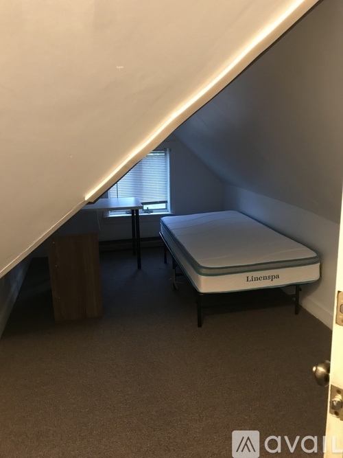 A small bedroom with a single bed and a wooden stool.