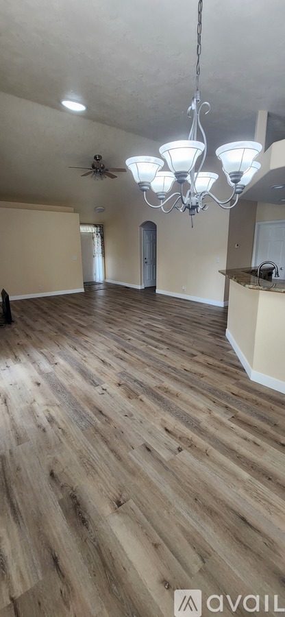 A room with wooden flooring and a chandelier hanging from the ceiling.