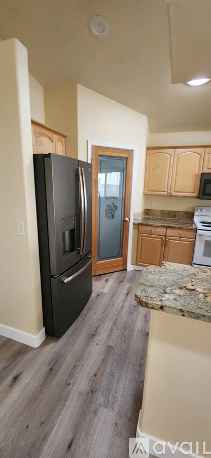 A kitchen with a granite counter top and wooden cabinets.