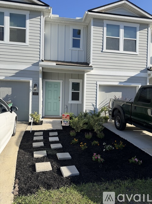 A white house with a green door and a white car parked in front.
