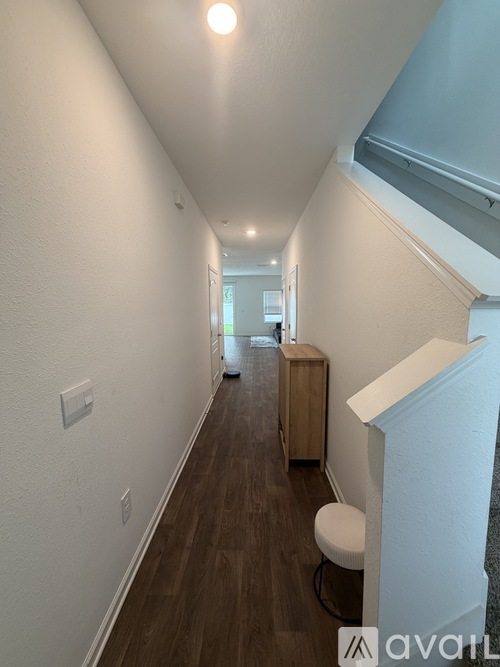 A long hallway with a white chair and a white cabinet.