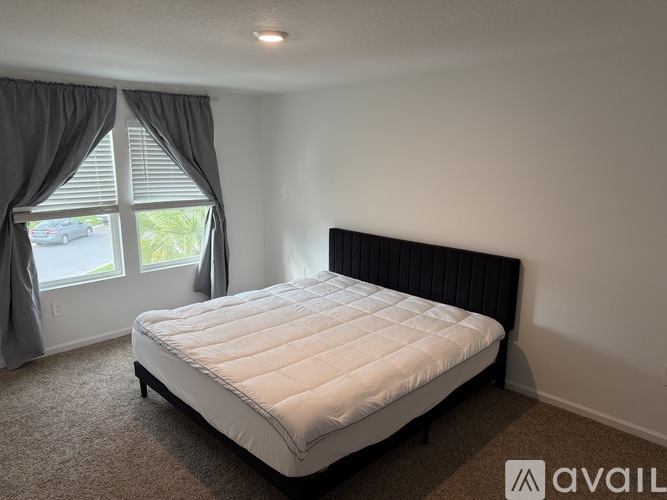 A bedroom with a large bed and a window with curtains.