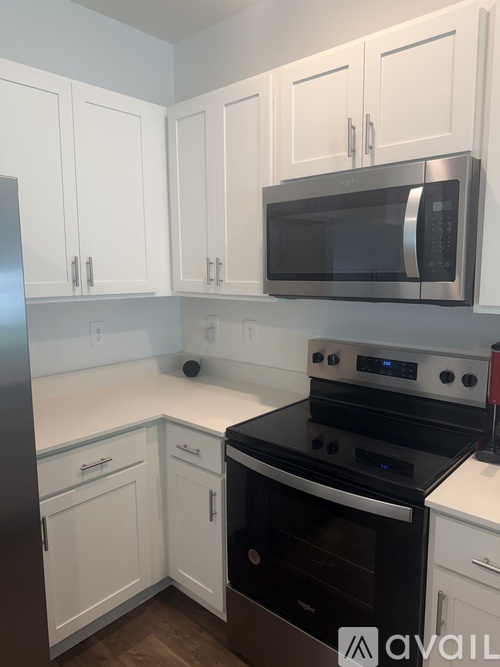 A kitchen with white cabinets and a black microwave.