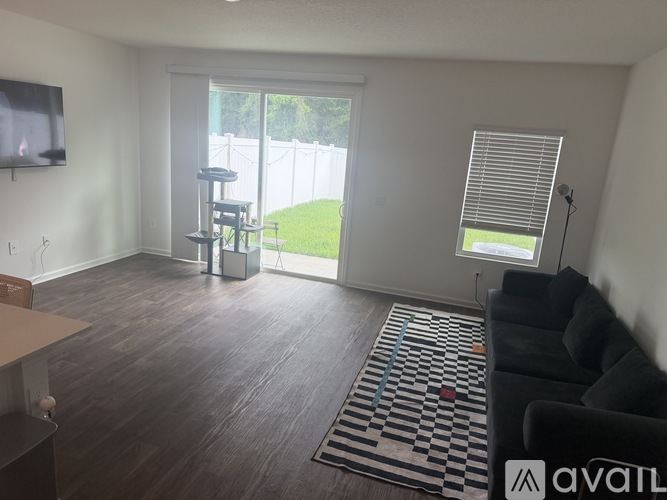 A living room with a black couch and a television on the wall.