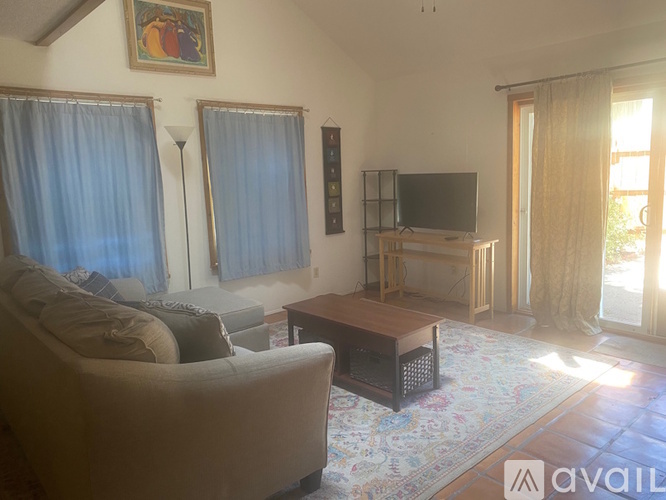 A living room with a couch, a coffee table, and a television.