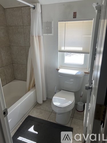 A bathroom with a toilet, tub, and window.