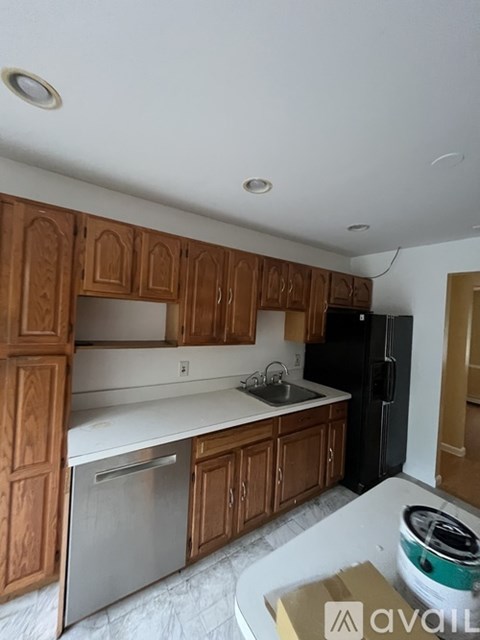 A kitchen with wooden cabinets and a black refrigerator.