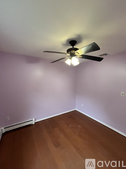 A room with a ceiling fan and wooden flooring.