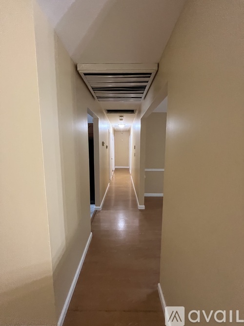 A long hallway with a light brown floor and white walls.