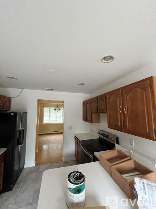 A kitchen with brown cabinets and a black fridge.