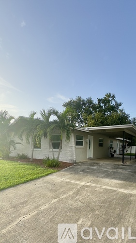 A house with a driveway and a tree in front.