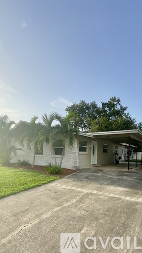 A house with a driveway and a tree in front.