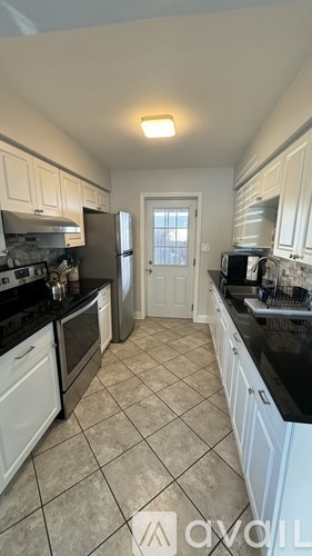 A kitchen with white cabinets and black countertops.
