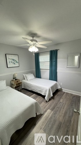 A bedroom with two beds and a ceiling fan.