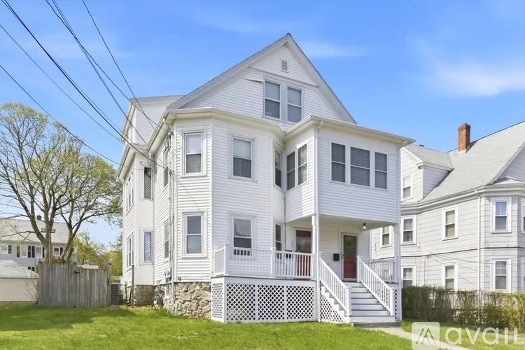 A white two-story house with a porch and a balcony.