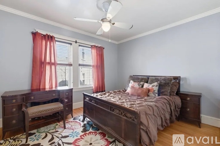 A bedroom with a large bed and a window with red curtains.