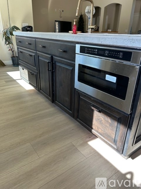 A modern kitchen with a stainless steel oven and dark wood cabinets.