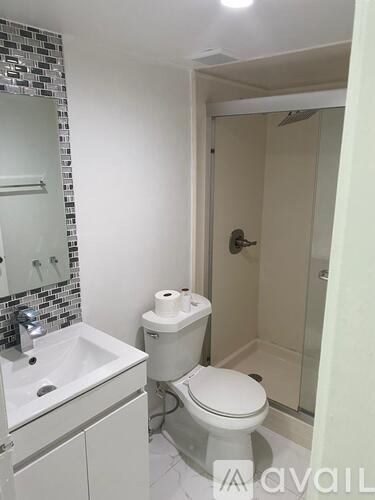 A white toilet with a roll of toilet paper on top of it.