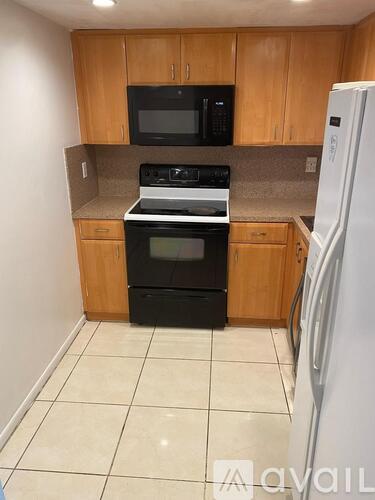 A kitchen with a white fridge, black microwave, black oven and wooden cabinets.