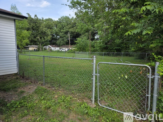A chain link fence separates a grassy area from a residential area.