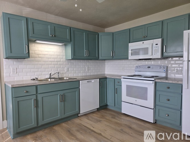A kitchen with green cabinets and white appliances.