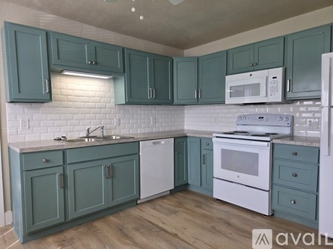 A kitchen with green cabinets and white appliances.