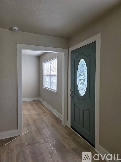 A room with a wooden floor and a green door.