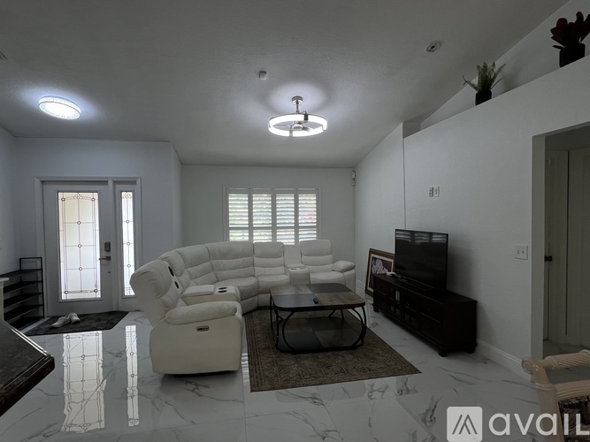 A living room with a white sofa set and a television.